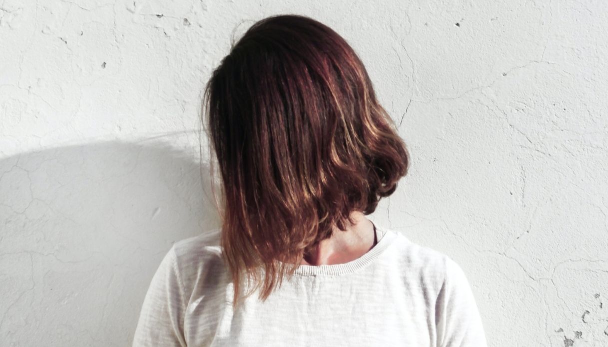 ragazza con capelli mori a caschetto asimmetrici con maglietta bianca su sfondo bianco