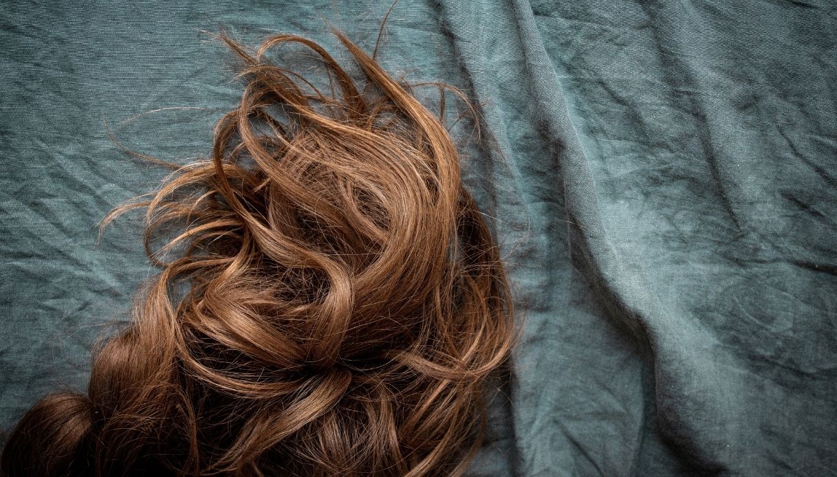 sfondo di tessuto verde con ciocche di capelli castano chiaro