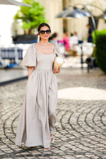 modella con abito beige e occhiali da sole neri