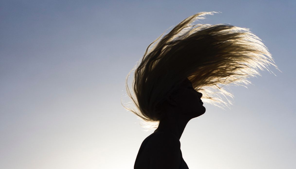 ragazza che lancia i capelli in aria al tramonto