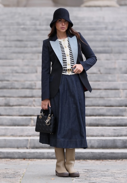 donna con gonna a ruota blu, cappotto blu e stivali marroni