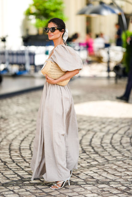 Donna che indossa abito beige e. borsa di paglia