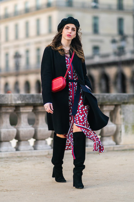 Modella con vestito in fantasia rosso, borsa rossa e cappotto, cappello e stivali neri