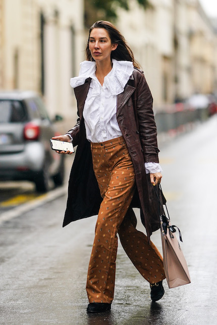donna con camicia con colletto, cappotto marrone e pantaloni in fantasia
