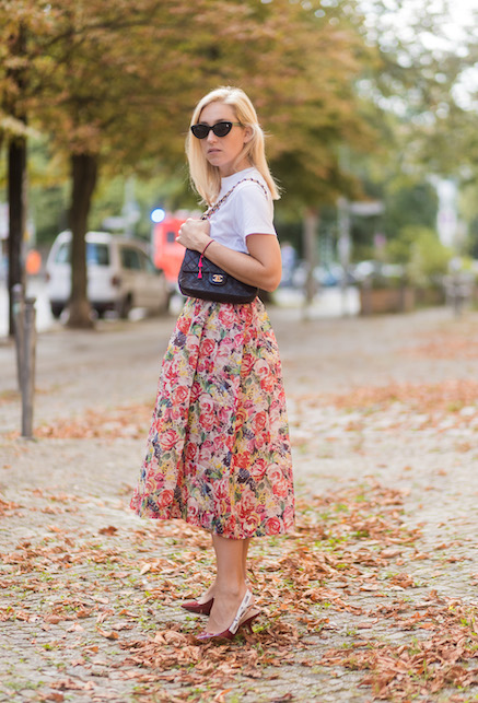 Donna con t-shirt bianca, borsa nera e gonna a fiori
