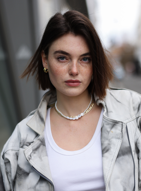 modella con collana dorata, giacca chiara e maglietta bianca
