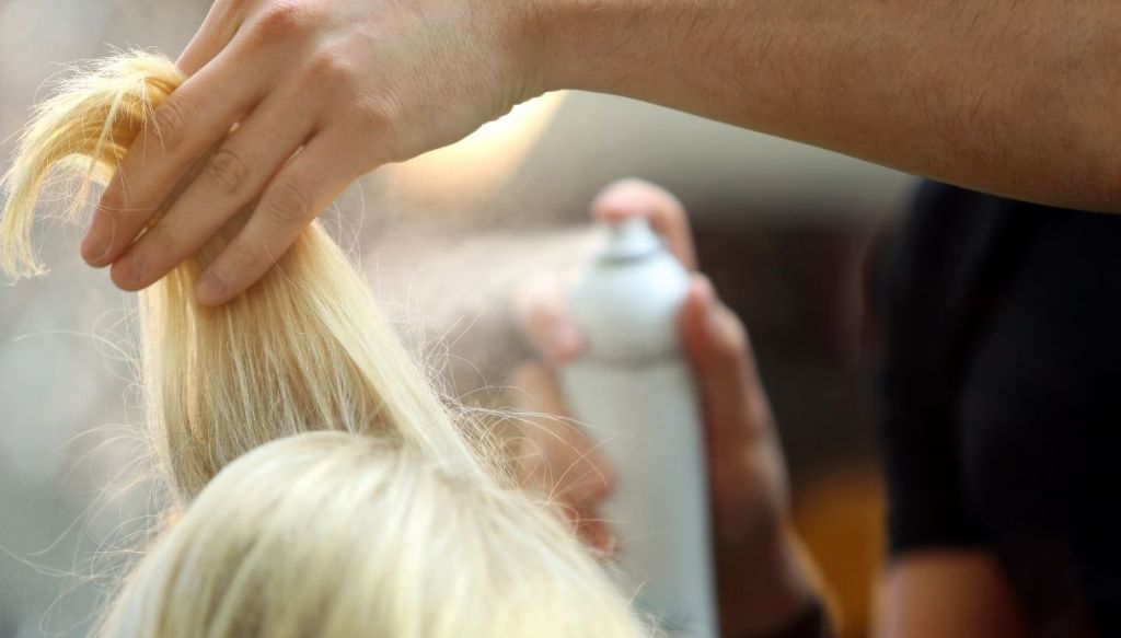 mano spruzza lacca shampoo secco su ciocca capelli biondi