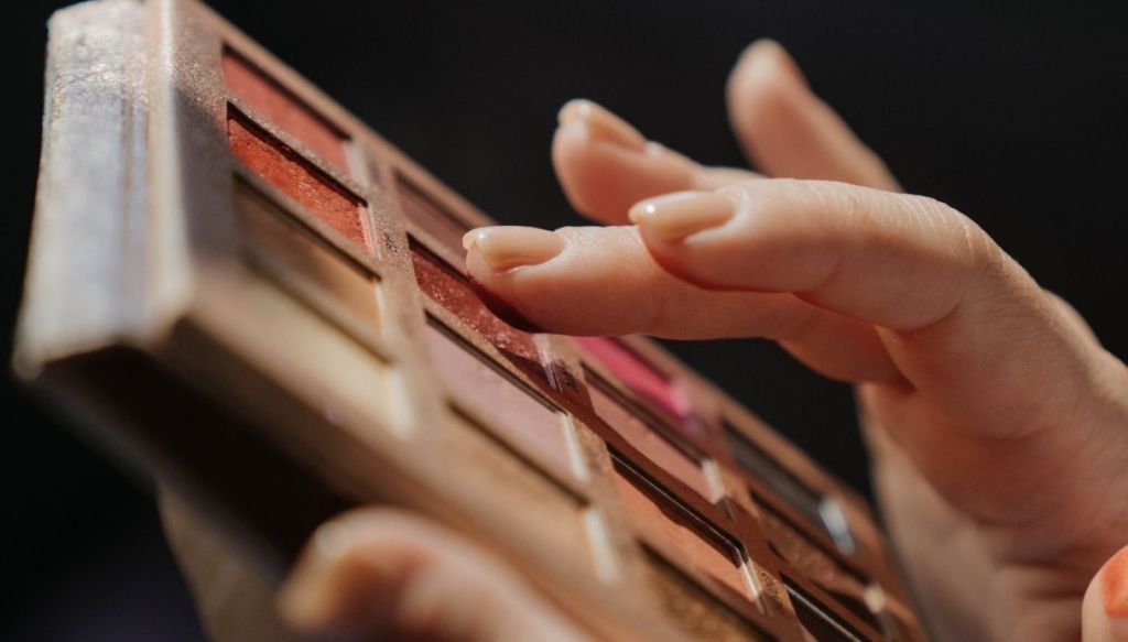 mano preleva ombretti da una palette colorata