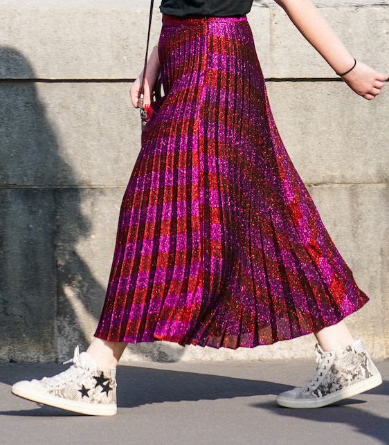 ragazza con gonna rossa e fucsia e sneakers con le stelle