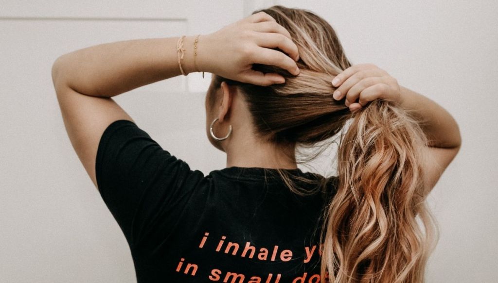 Ragazza di spalle fa coda alta capelli biondi mossi