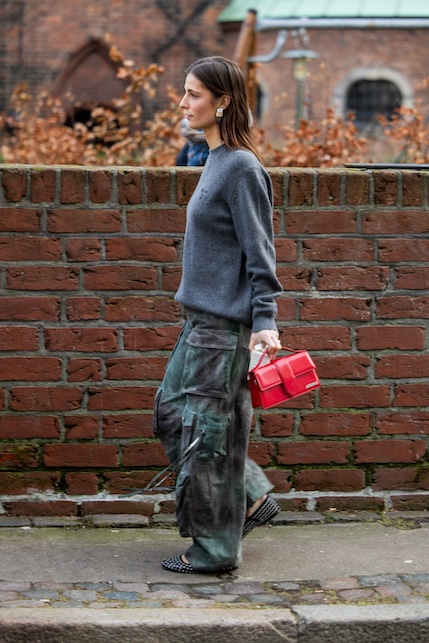 ragazza con maglione grigio, borsa rossa e e pantaloni camoflage