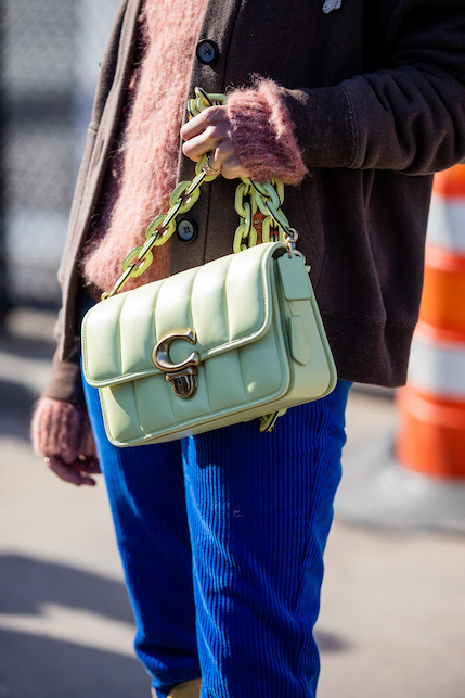 ragazza con borsa verde menta, giacca marrone e pantaloni bluette