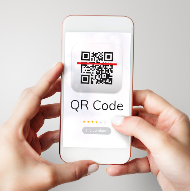 mani che tengono un telefono con un QR code