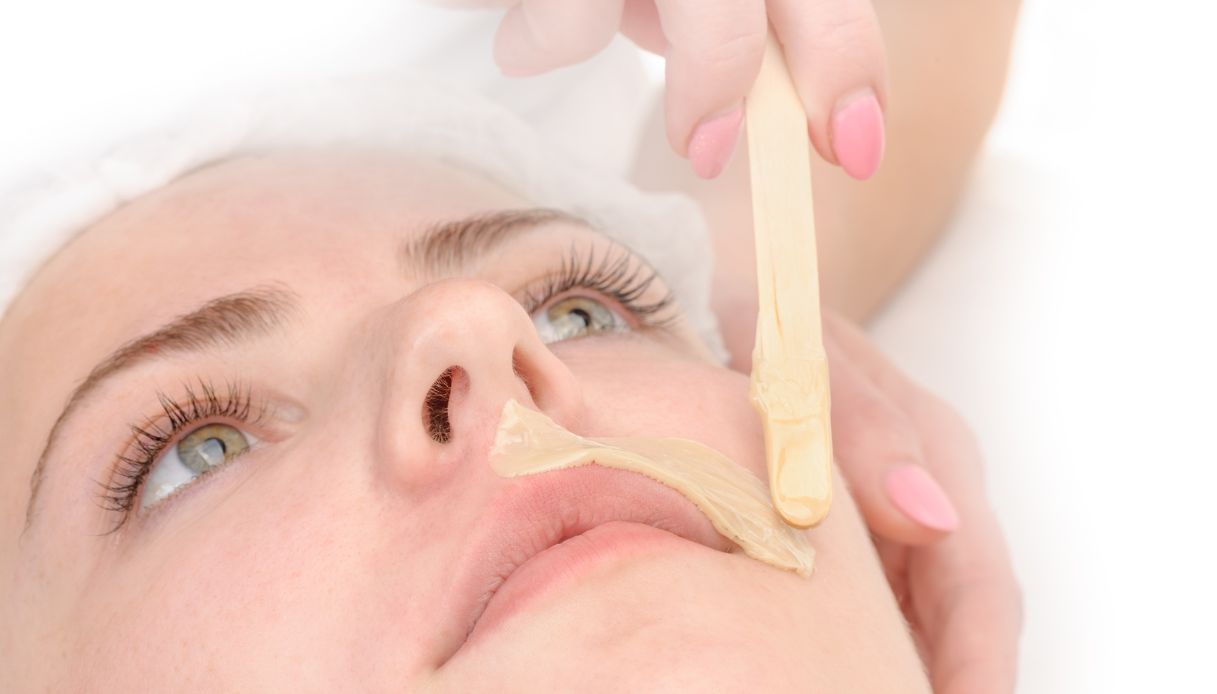 primo piano viso di donna con cuffia che fa cera ai baffetti