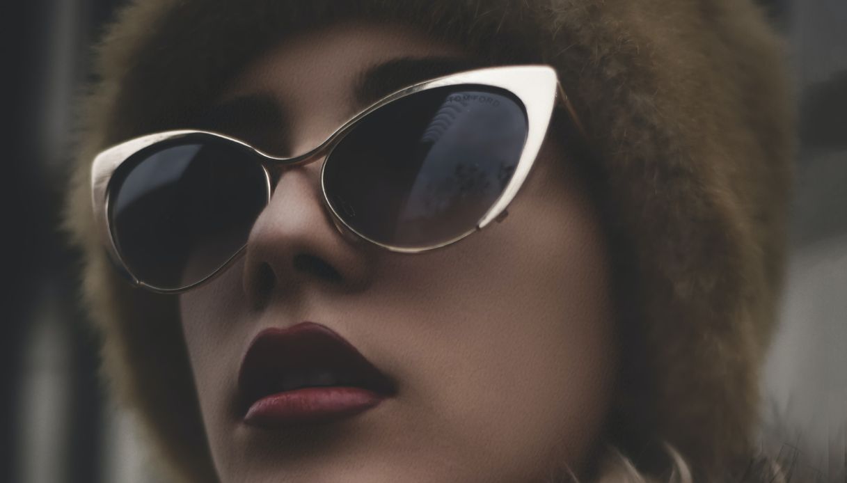 donna con rossetto scuro e occhiali grandi a farfalla dorati