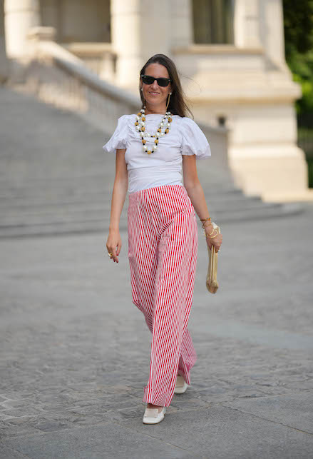 ragazza con pantaloni palazzo a righe bianche e rosse, t-shirt bianca e accessori dorati