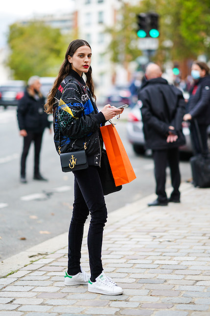 ragazza con giacca e pantaloni neri e sneakers bianche