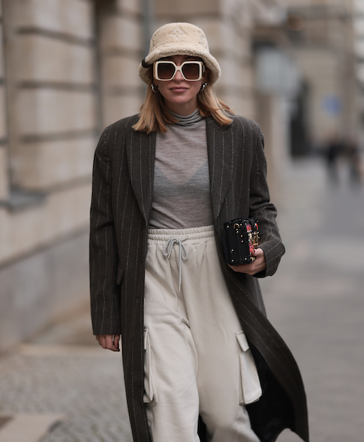 ragazza con bucket hat occhiali e cappotto