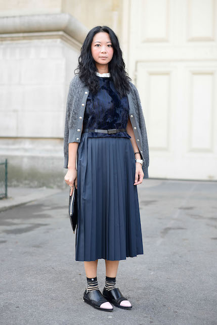 ragazza con gonna a pieghe blu e golfino grigio