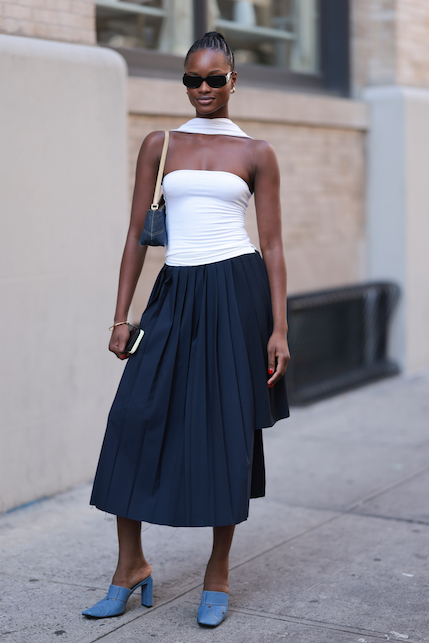 ragazza con gonna a pieghe blu e top bianco