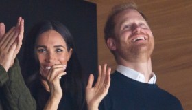 Harry e Meghan Markle allo stadio: lui imita Elisabetta II, lei ha un look da 143.455 euro
