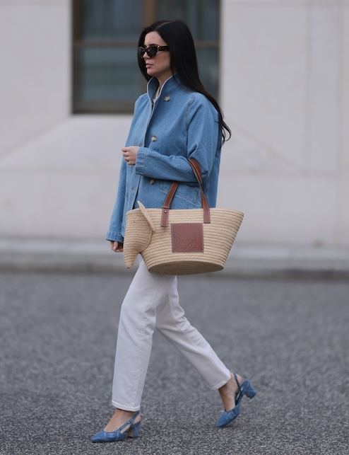 ragazza con jeans bianchi, giacca jeans e borsa di paglia