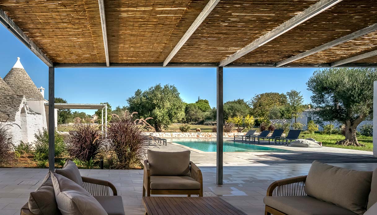 La veranda ombreggiata si affaccia sulla piscina, creando un perfetto spazio di relax immerso nel paesaggio pugliese