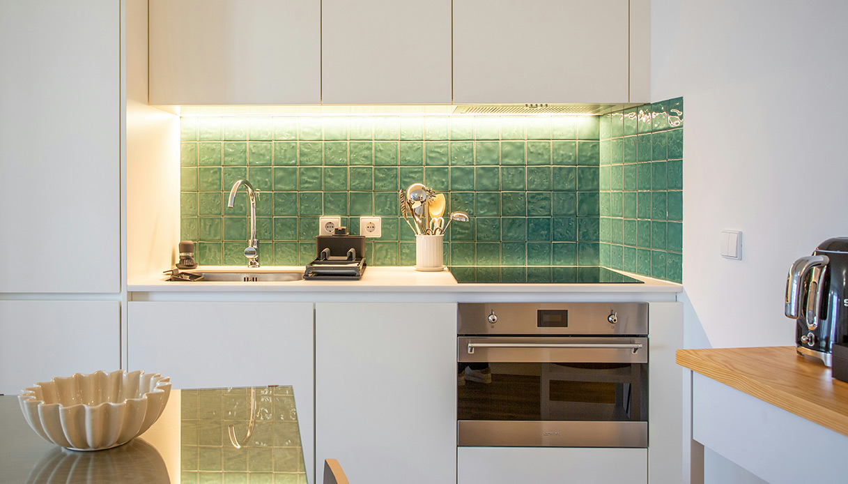 Cucina compatta e luminosa con rivestimento verde brillante: funzionalità ed eleganza in pochi metri quadri