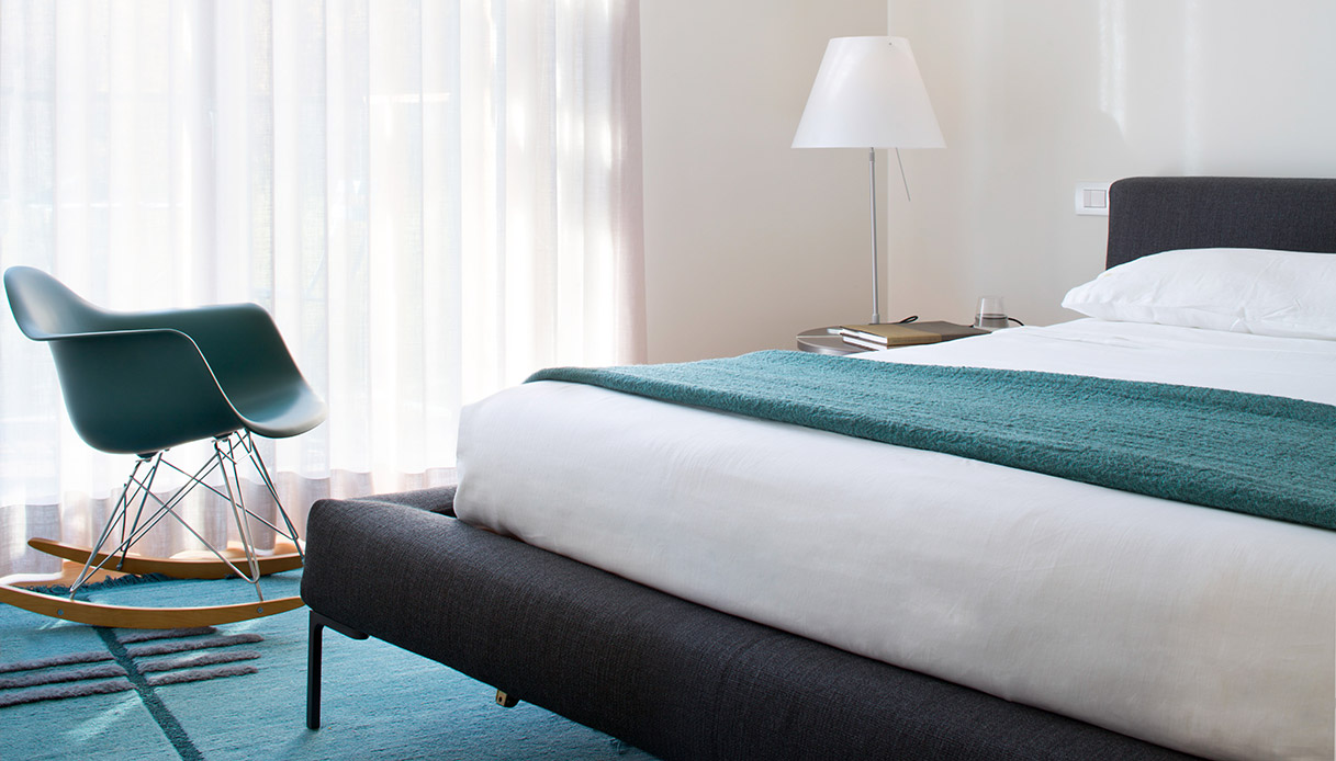 Nella camera padronale, il letto Charles di B&B Italia si accompagna alla celebre Eames Rocking Chair: un mix di comfort e stile senza tempo