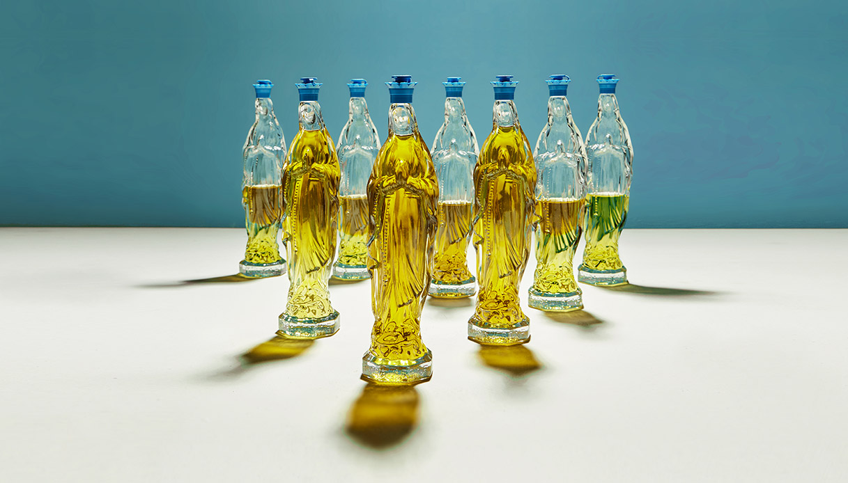Bottiglie di vetro trasparente a forma di Madonna riempite con olio extravergine d’oliva