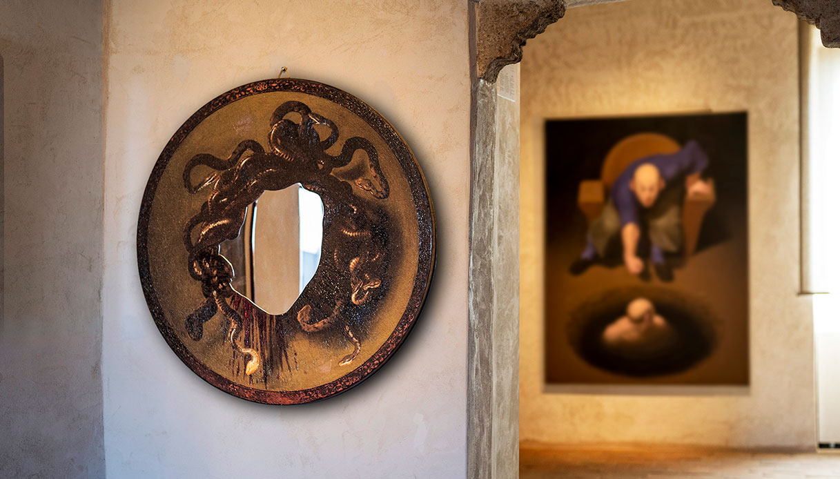 Specchio decorativo circolare con cornice scura e figura di Medusa scolpita