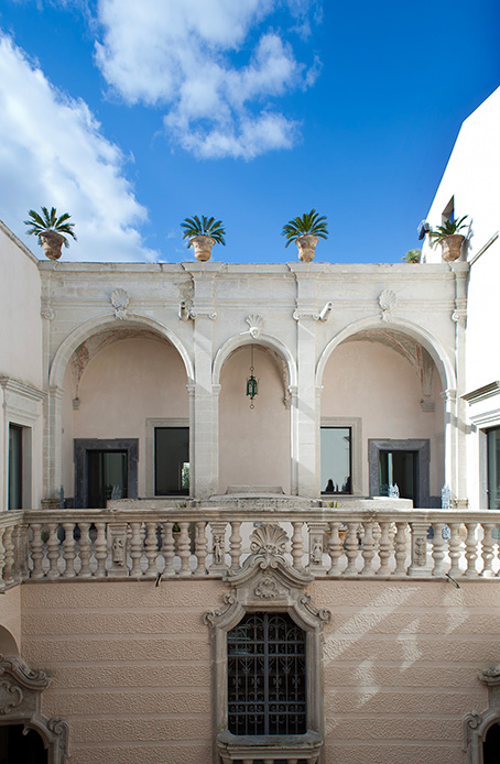 Balconata barocca in pietra leccese con vasi e cielo azzurro