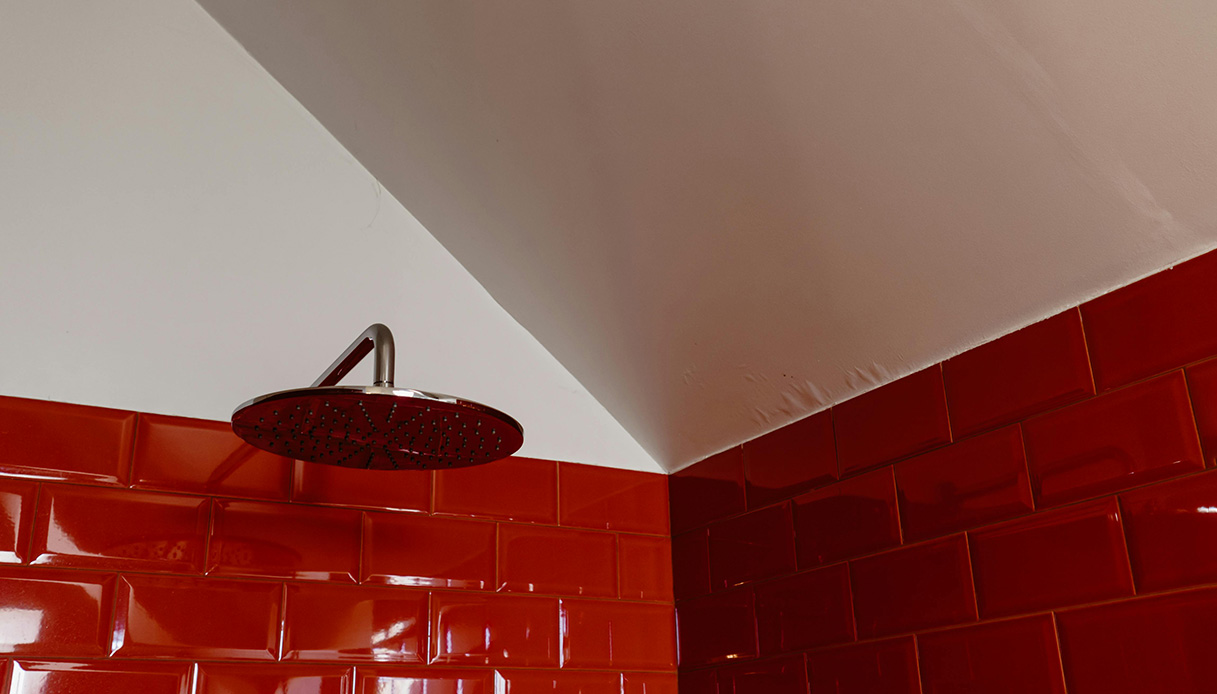 Piastrelle rosse in bagno con doccia a pioggia