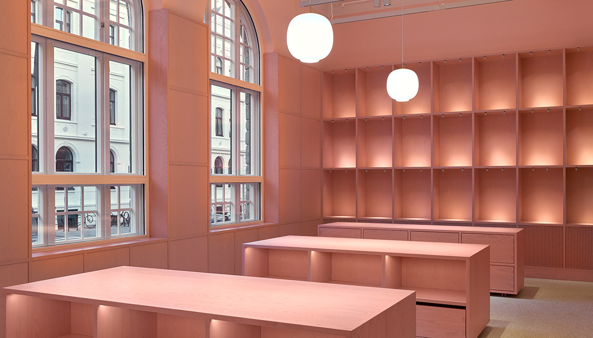Interni del bookshop del museo PoMo con pareti rosa e scaffalature illuminate