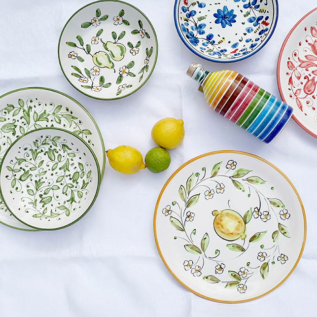 Piatti in ceramica pugliese con motivi di limoni e rami d’ulivo su sfondo bianco