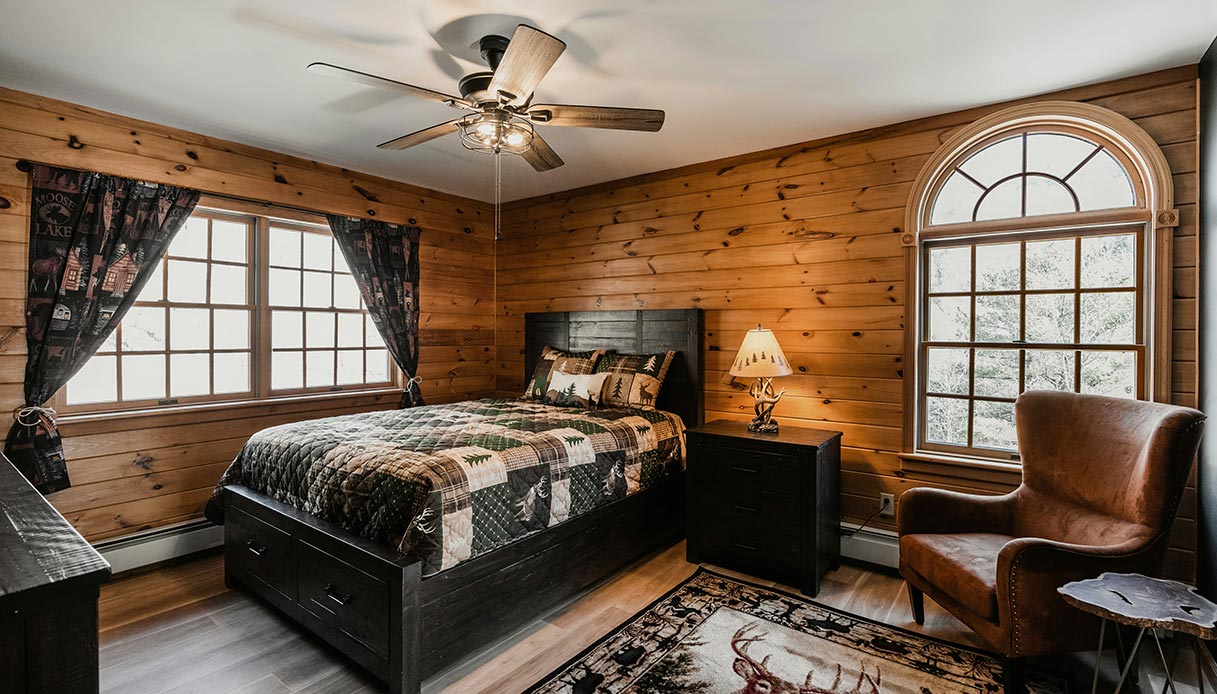 Ventilatore in camera da letto dallo stile rustico con pareti in legno